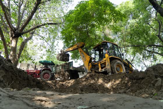 Clearing and hauling: backhoe and tractor working together.